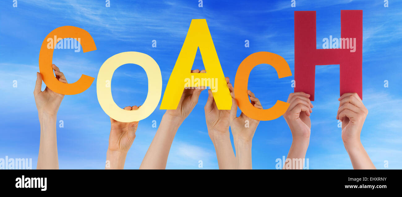 Viele Hände halten bunte Buchstaben oder Zeichen Gebäude der englischen Wort Trainer auf blauen Himmel und kaukasische Menschen Stockfoto