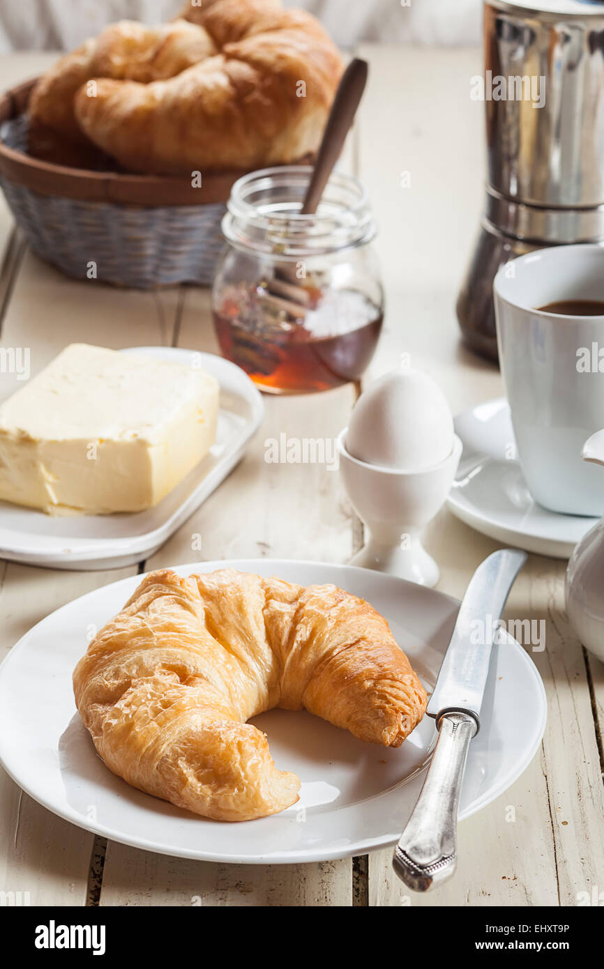 Frühstück mit Croissant, Ei, Kaffee, Honig und butter Stockfoto