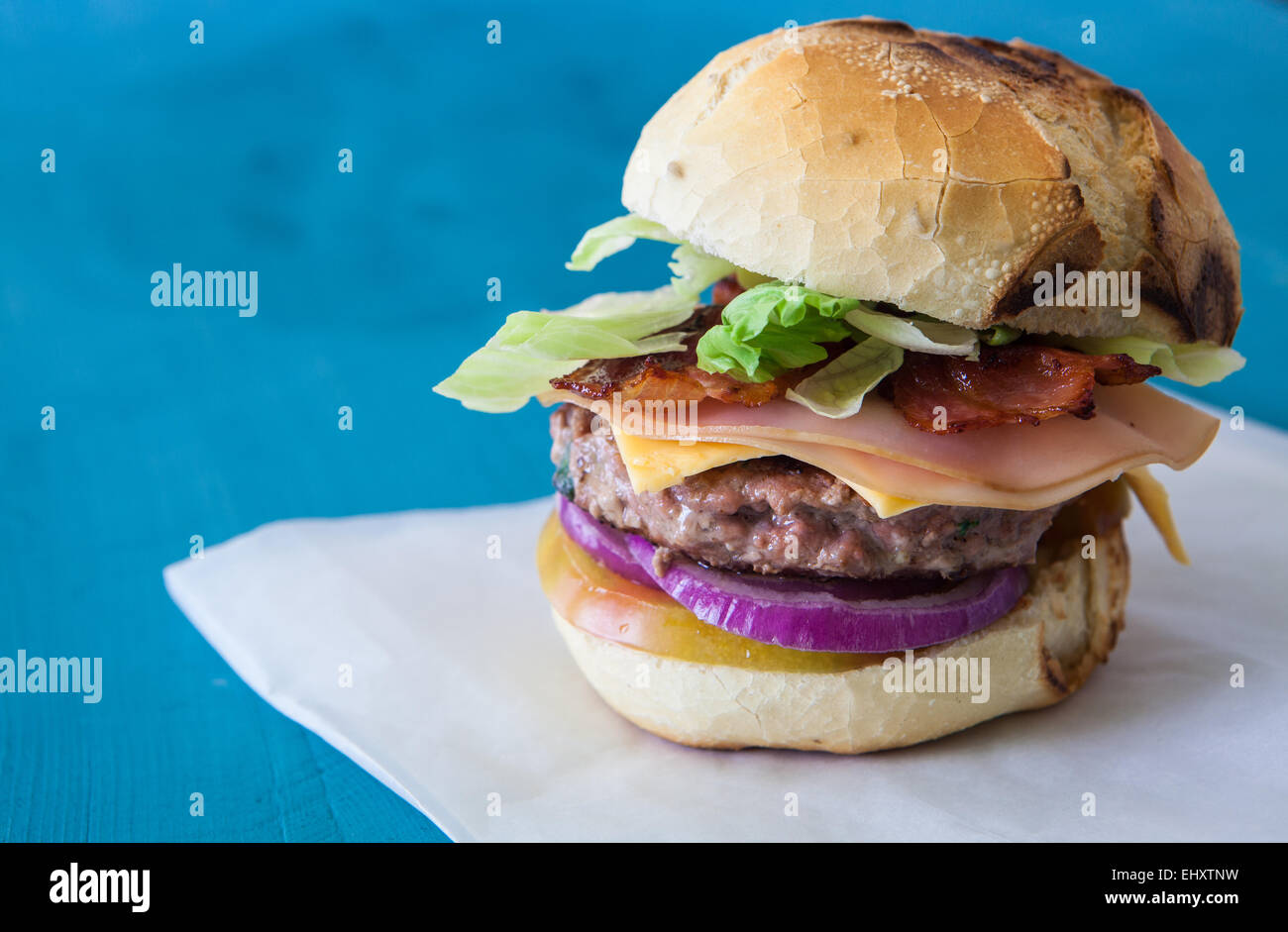 große Käse-Speck-Burger mit Zwiebeln und Salat Stockfoto