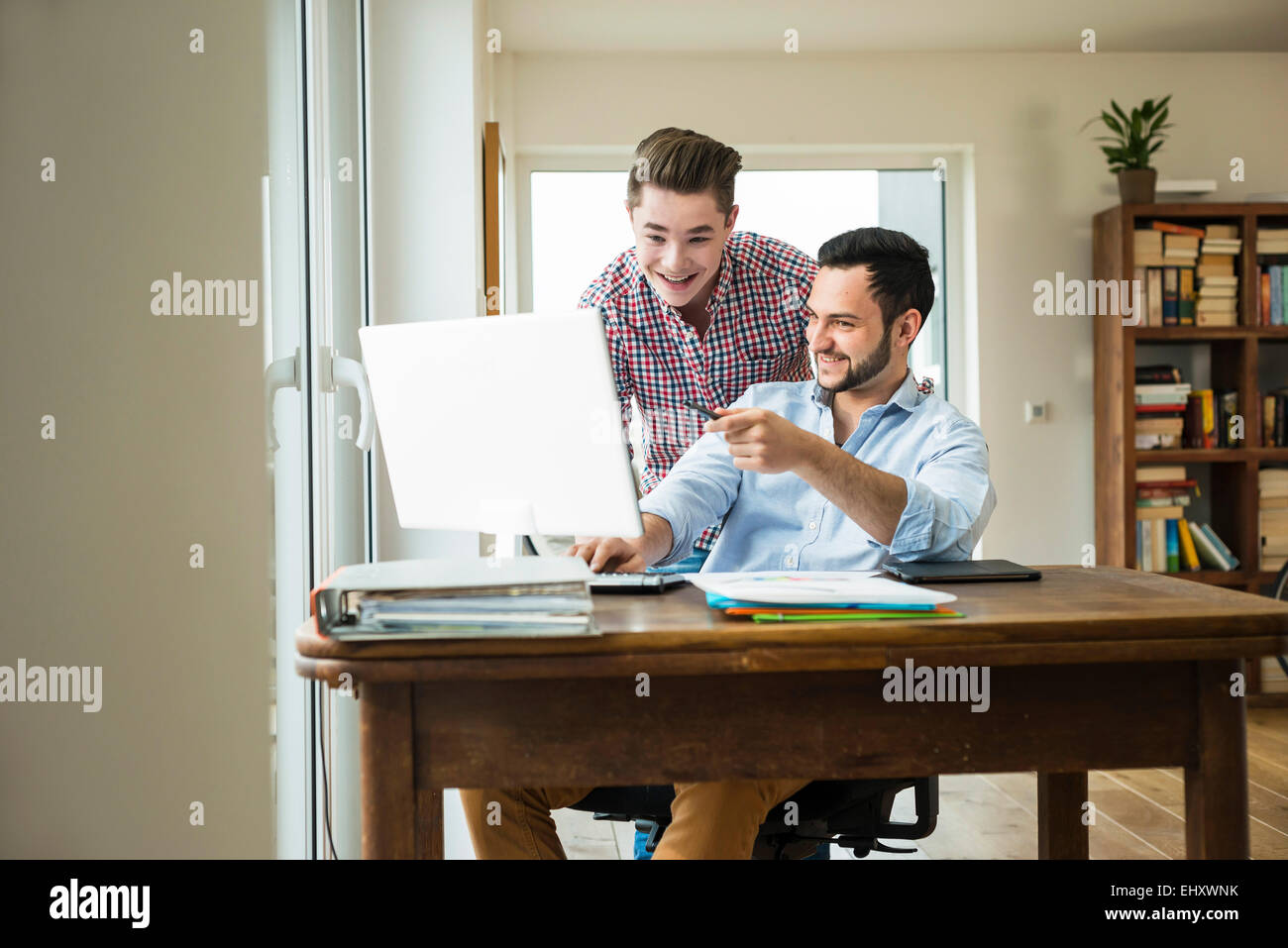 Zwei lächelnde junge Männer auf der Suche am Computer-monitor Stockfoto