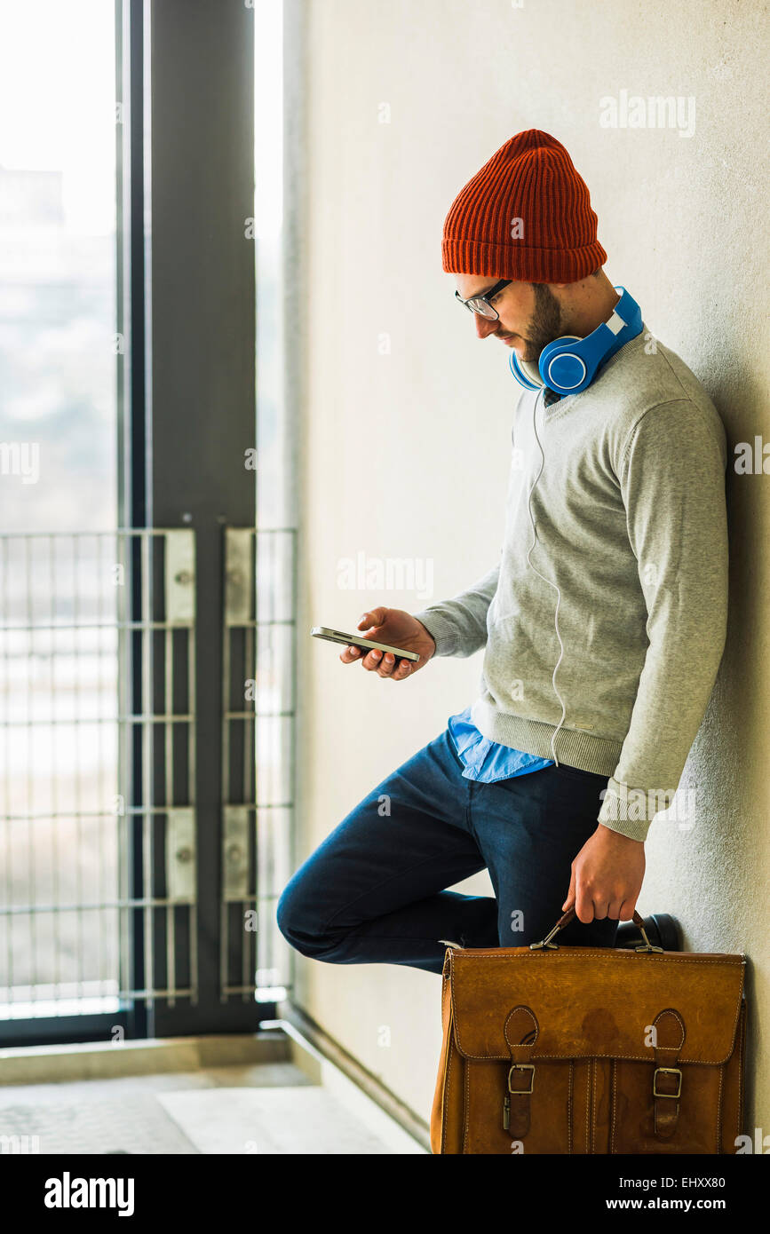 Junger Mann mit Blick auf Handy-Ledertasche Stockfoto