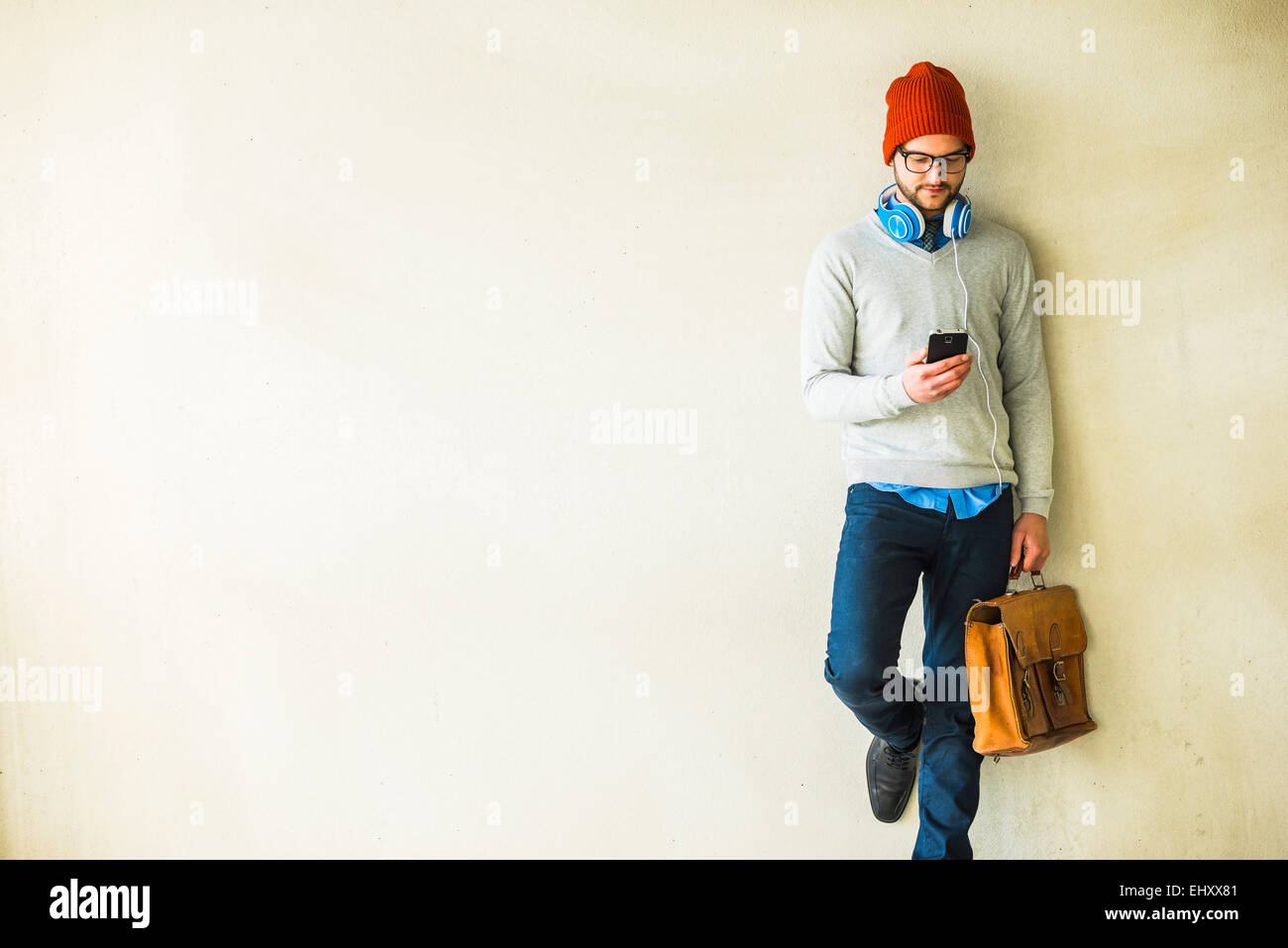 Junger Mann mit Blick auf Handy-Ledertasche Stockfoto