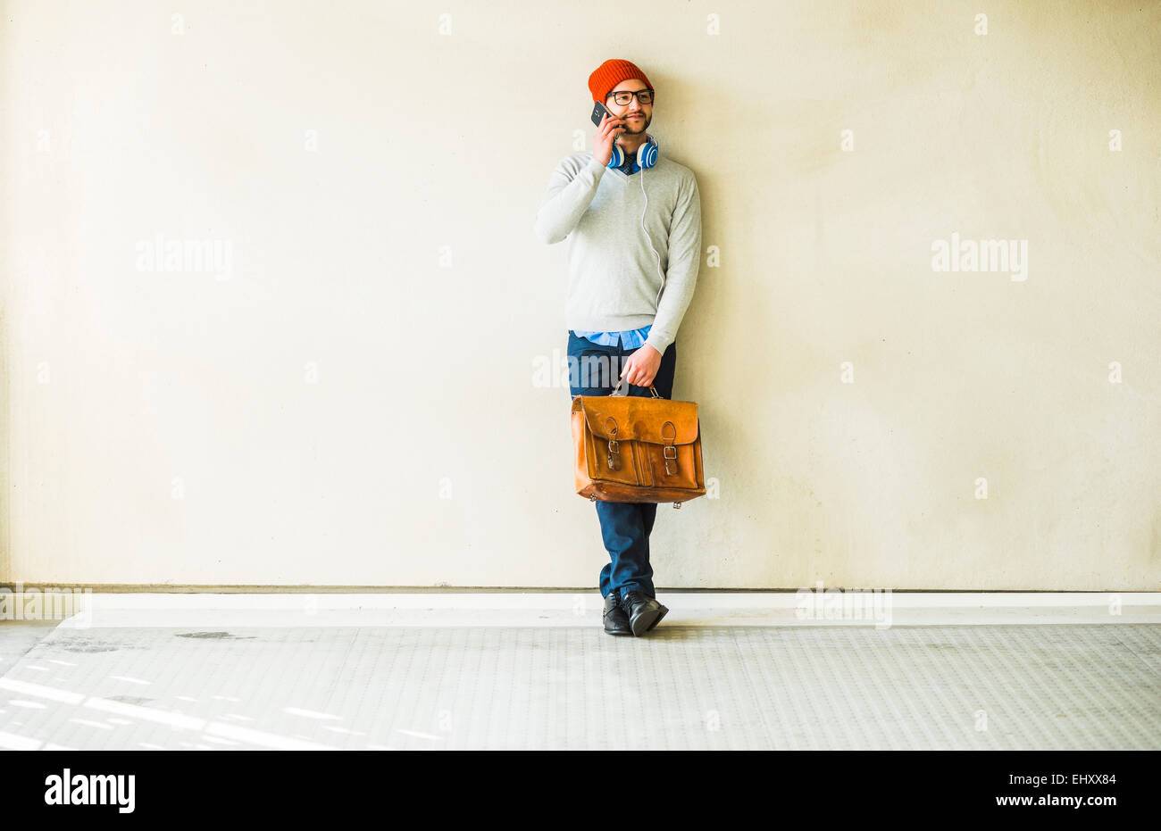 Junger Mann mit Ledertasche reden über Handy Stockfoto