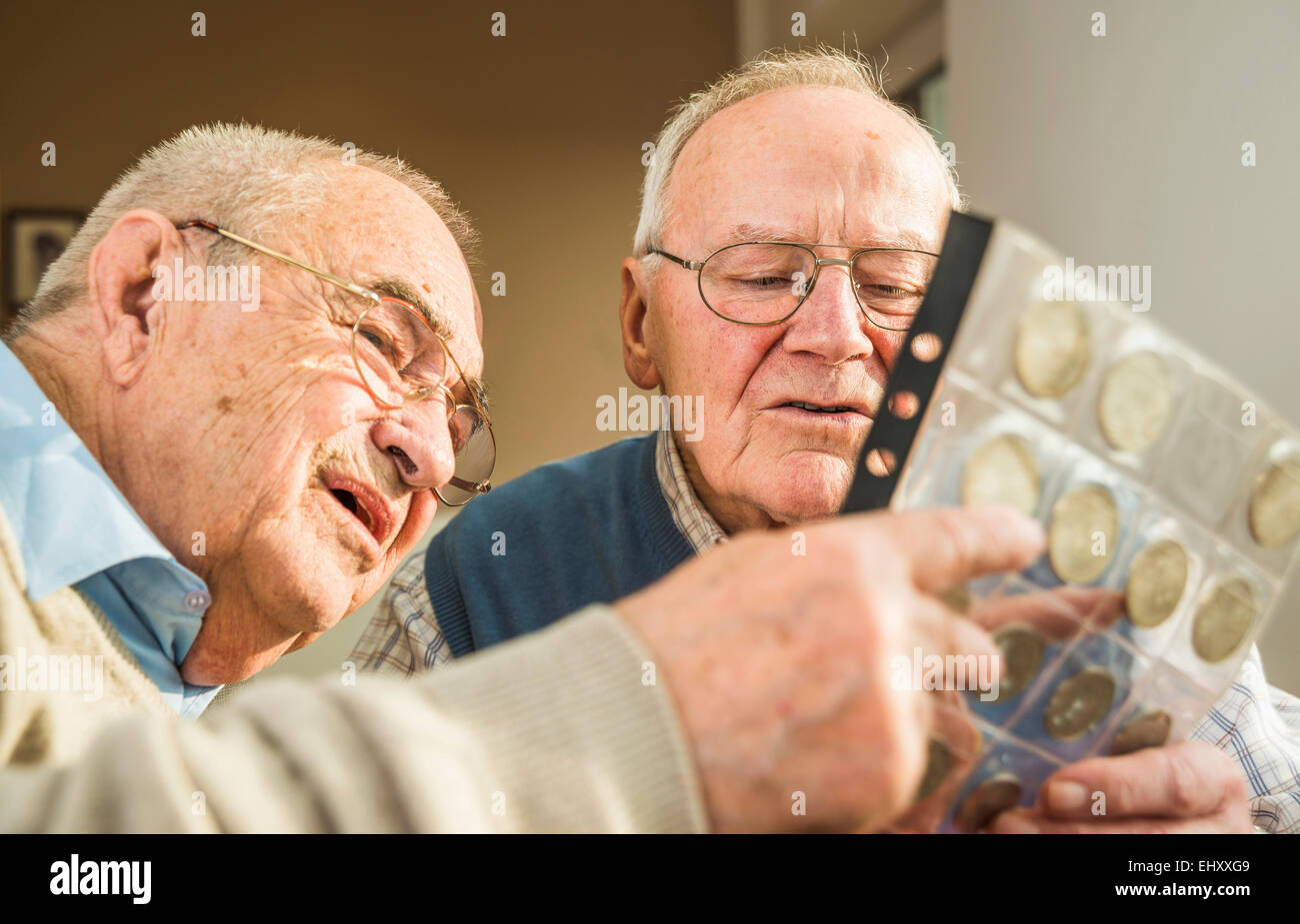 Zwei Senioren Freunde mit Münzenalbum Stockfoto