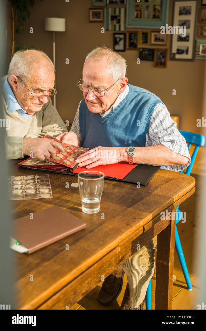 Zwei Senioren Freunde mit Münzenalbum Stockfoto