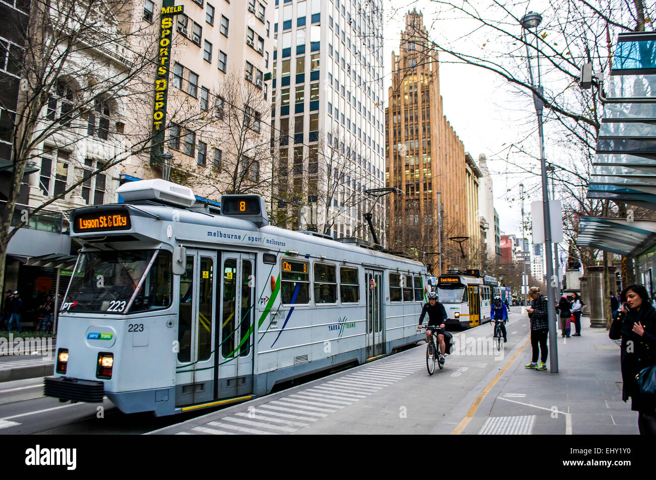 Blauen Straßenbahnen Line-up für Passagiere bei der Swanston Street im Herzen von Melbourne, Australien während Radfahrer vorbei in einen Radweg. Stockfoto