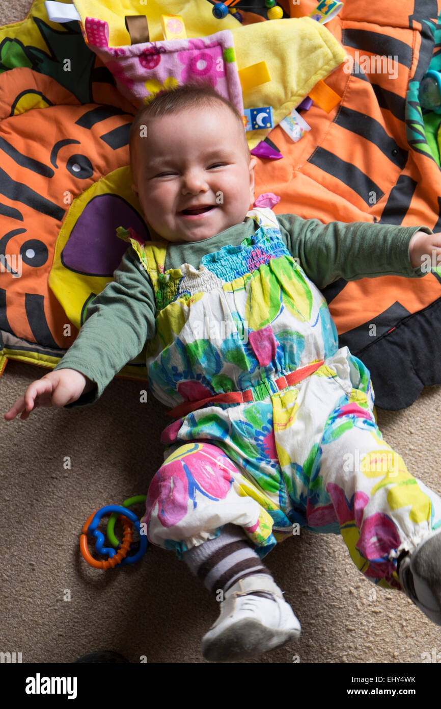8 Monate altes Baby Mädchen, liegend am Boden vor Lachen Stockfoto