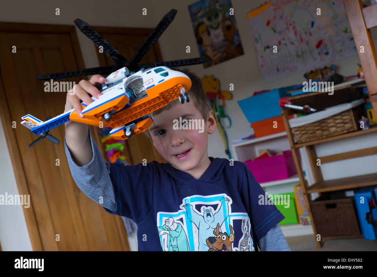 Jungen im Alter von vier Jahren spielen mit Lego Bausteinen Hubschrauber im Schlafzimmer Stockfoto