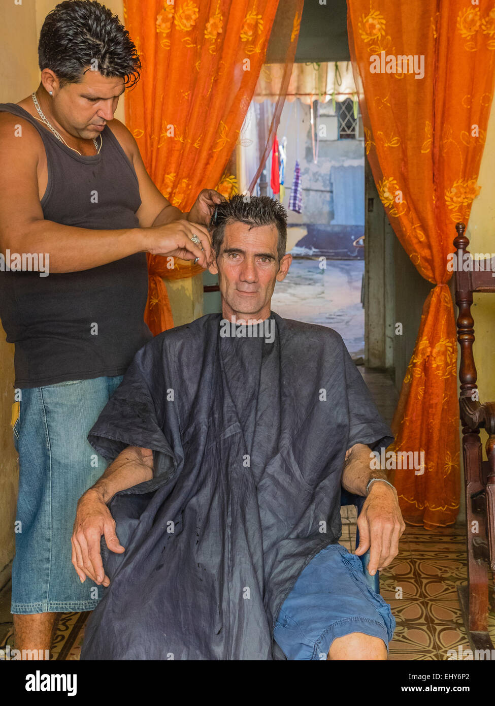 Ein kubanische Mann sitzt in der Friseur-Stuhl immer seine Haare schneiden und vorausschauend Sttraight In Havanna. Stockfoto