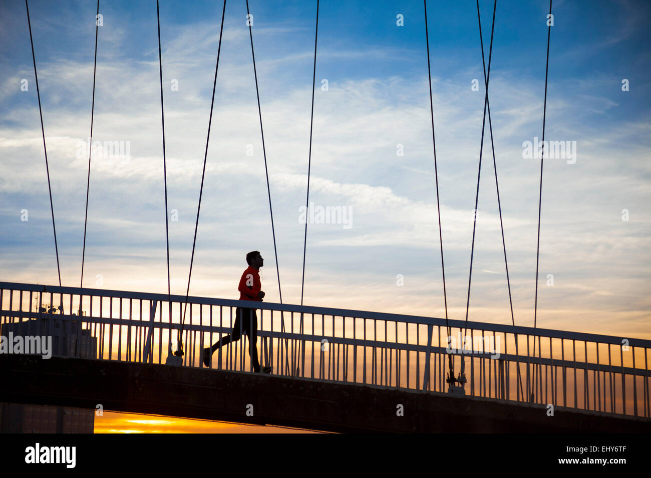 Mann, jogging auf Brücke bei Sonnenuntergang Stockfoto