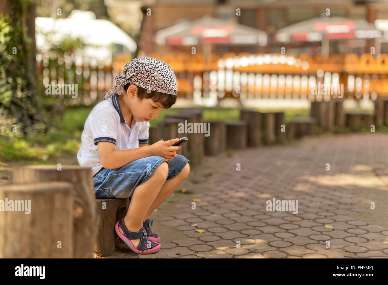 Junge sitzt im Park auf dem Handy spielen Stockfoto
