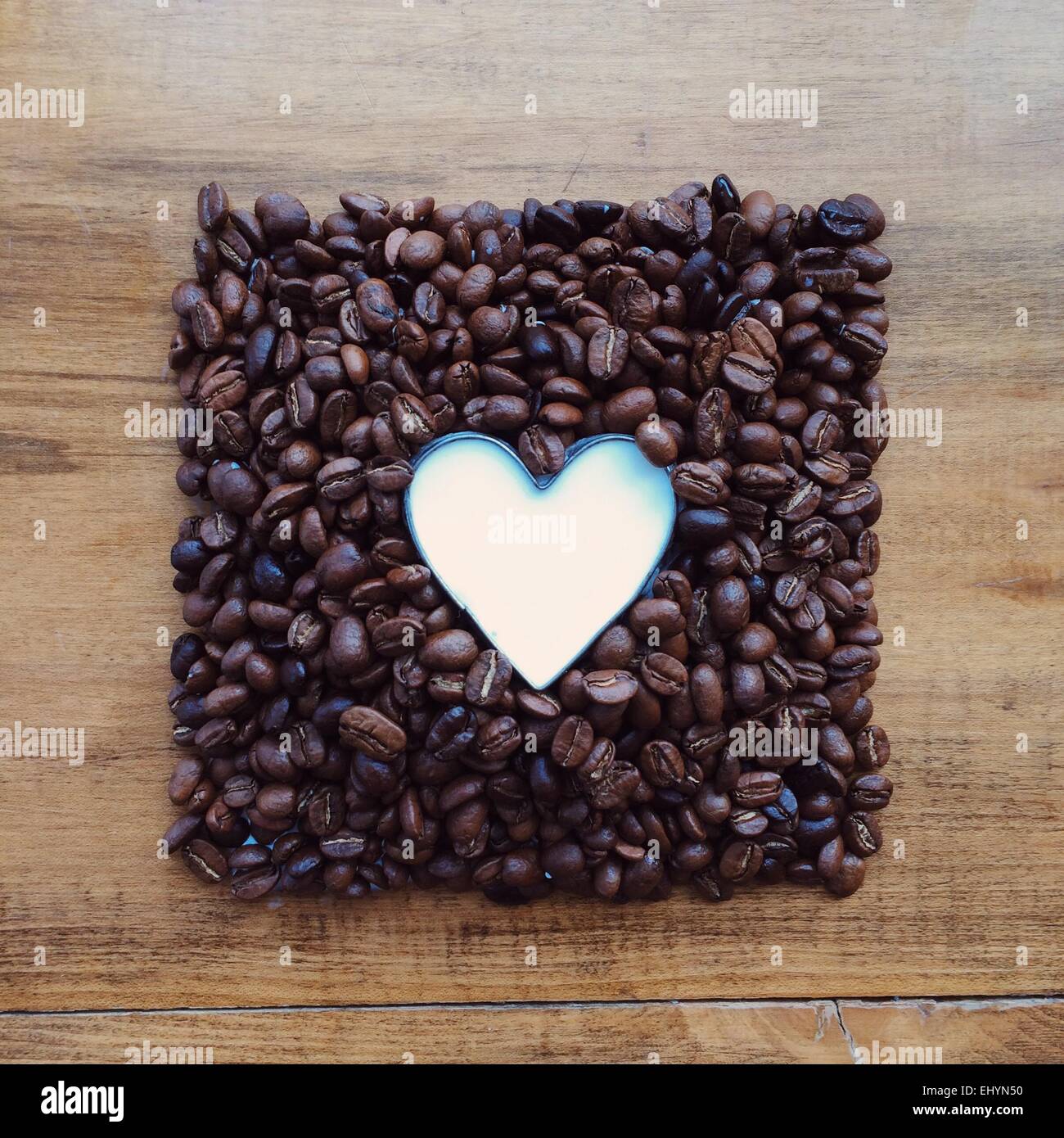 Kaffeebohnen im Quadrat, rund um ein Herz geformt Kaffeesahne Stockfoto