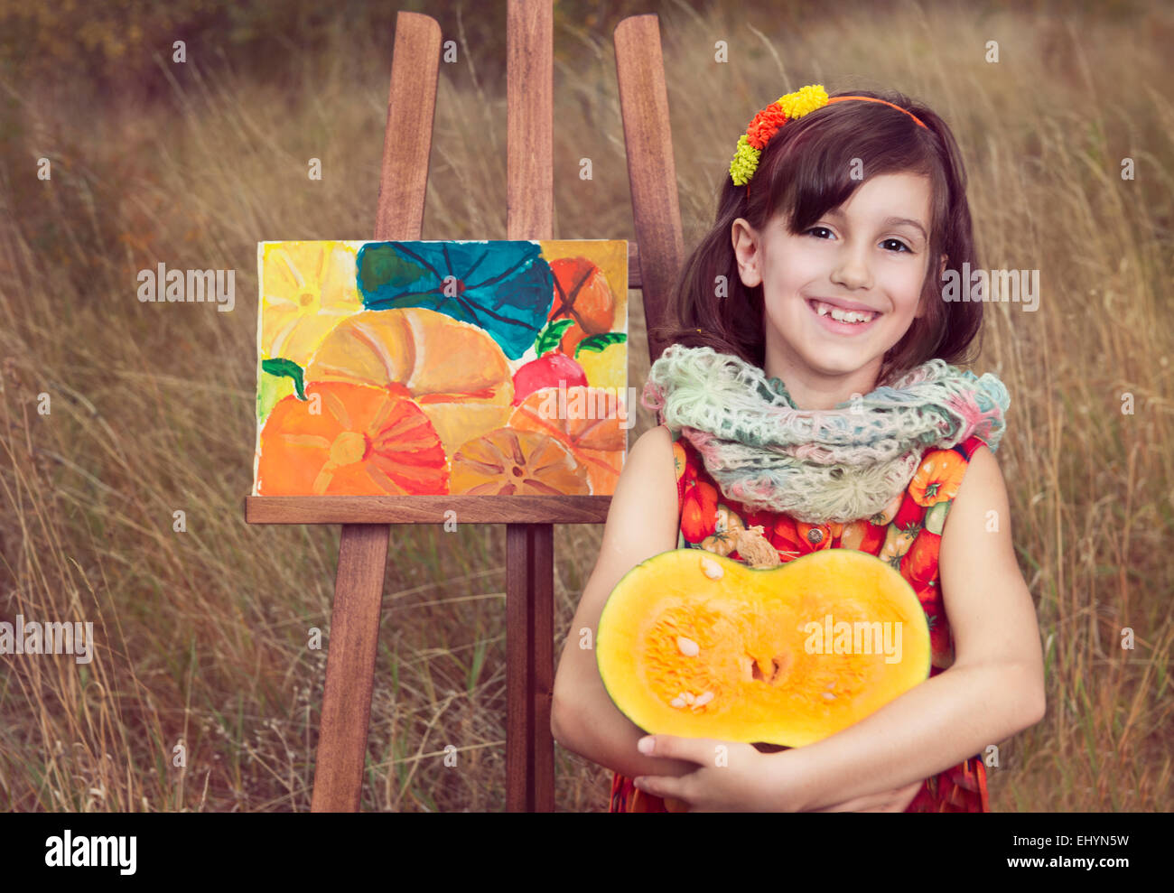 Mädchen sitzen mit Kürbis von einem Gemälde von Kürbissen Stockfoto