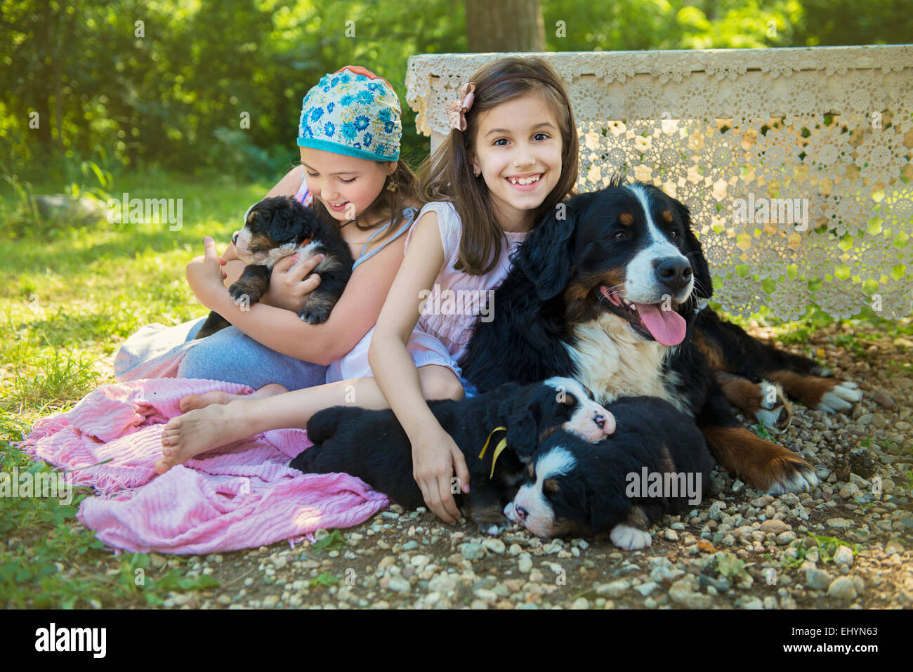 Zwei Mädchen sitzen im Garten mit einem Hund und Welpen Stockfoto