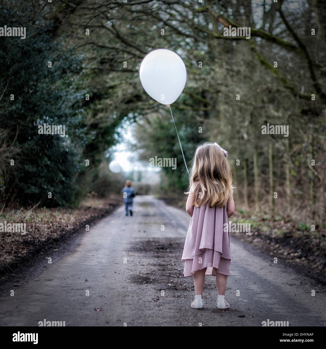 Rückansicht des Mädchens mit einem Ballon Blick auf junge auf der Flucht vor ihr Stockfoto