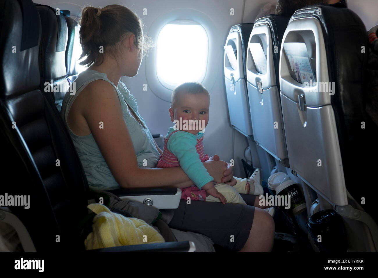 Mutter mit lächelnden Baby im Flugzeug reisen Stockfoto