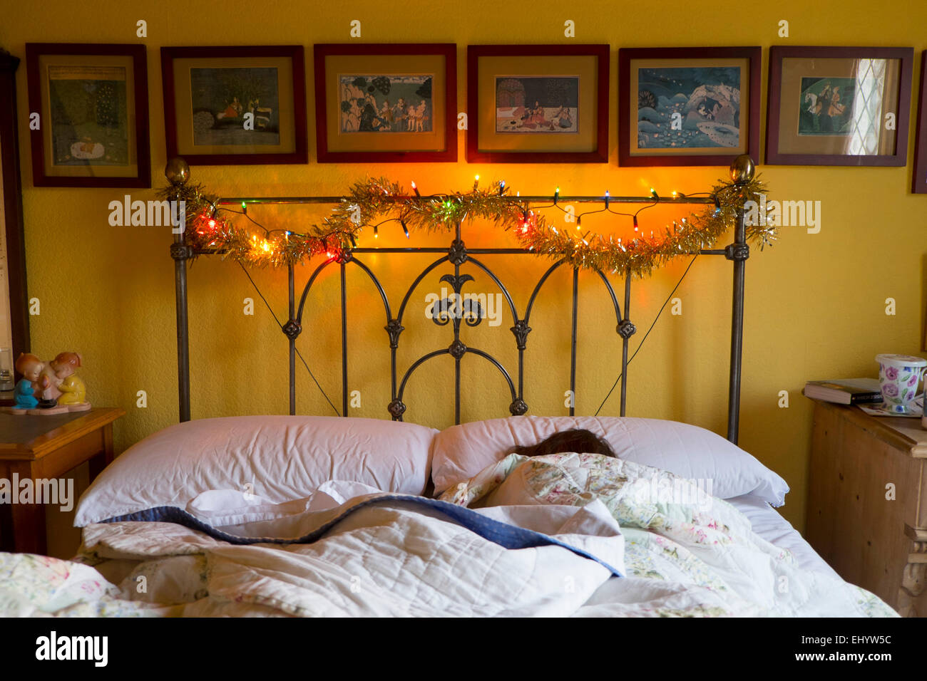 Frau schläft im Bett mit Weihnachtsbeleuchtung Stockfoto