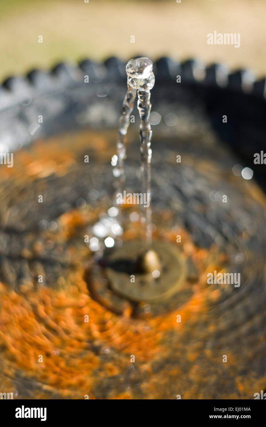 Wasser fließt aus einem Hahn in einem öffentlichen Brunnen und in einem rostigen Teller fallen. Selektiven Fokus Stockfoto