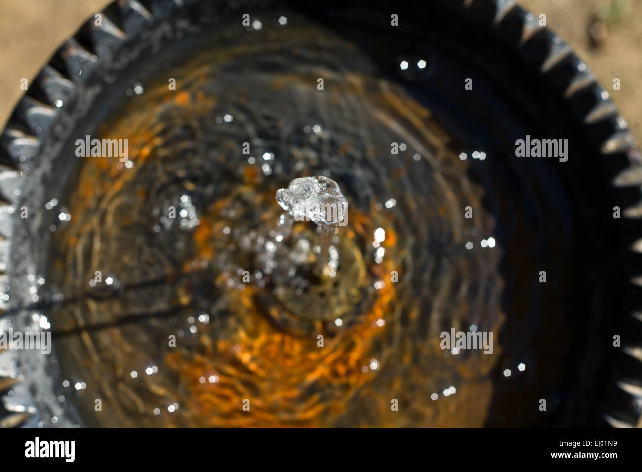 Wasser fließt aus einem Hahn in einem öffentlichen Brunnen und in einem rostigen Teller fallen. Selektiven Fokus Stockfoto