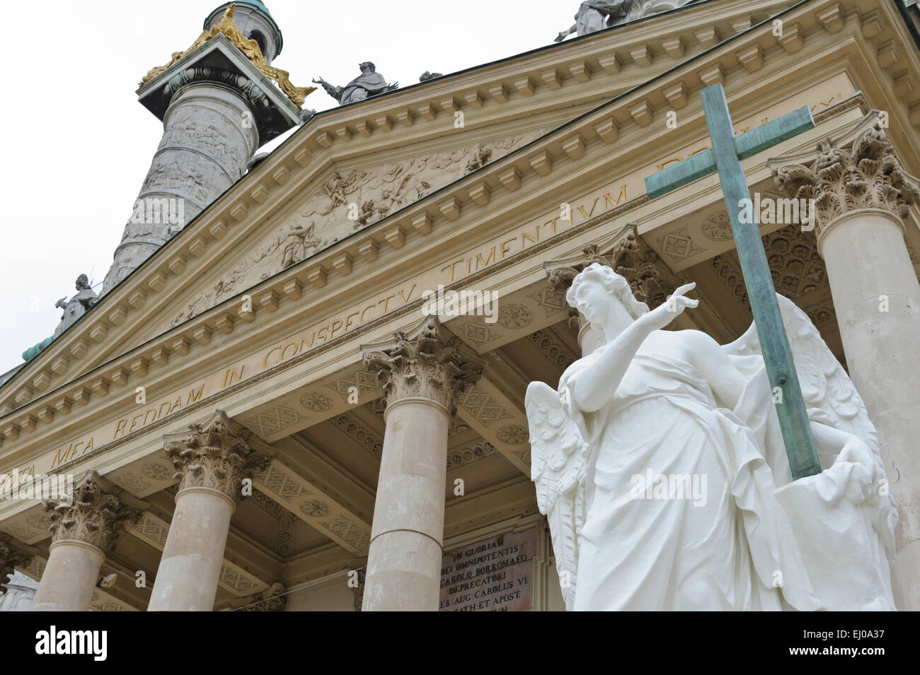 Eine Engelsstatue hält ein hölzernes Kreuz außerhalb der Karlskiche (St-Charles) Kirche, Wien, Österreich. Stockfoto