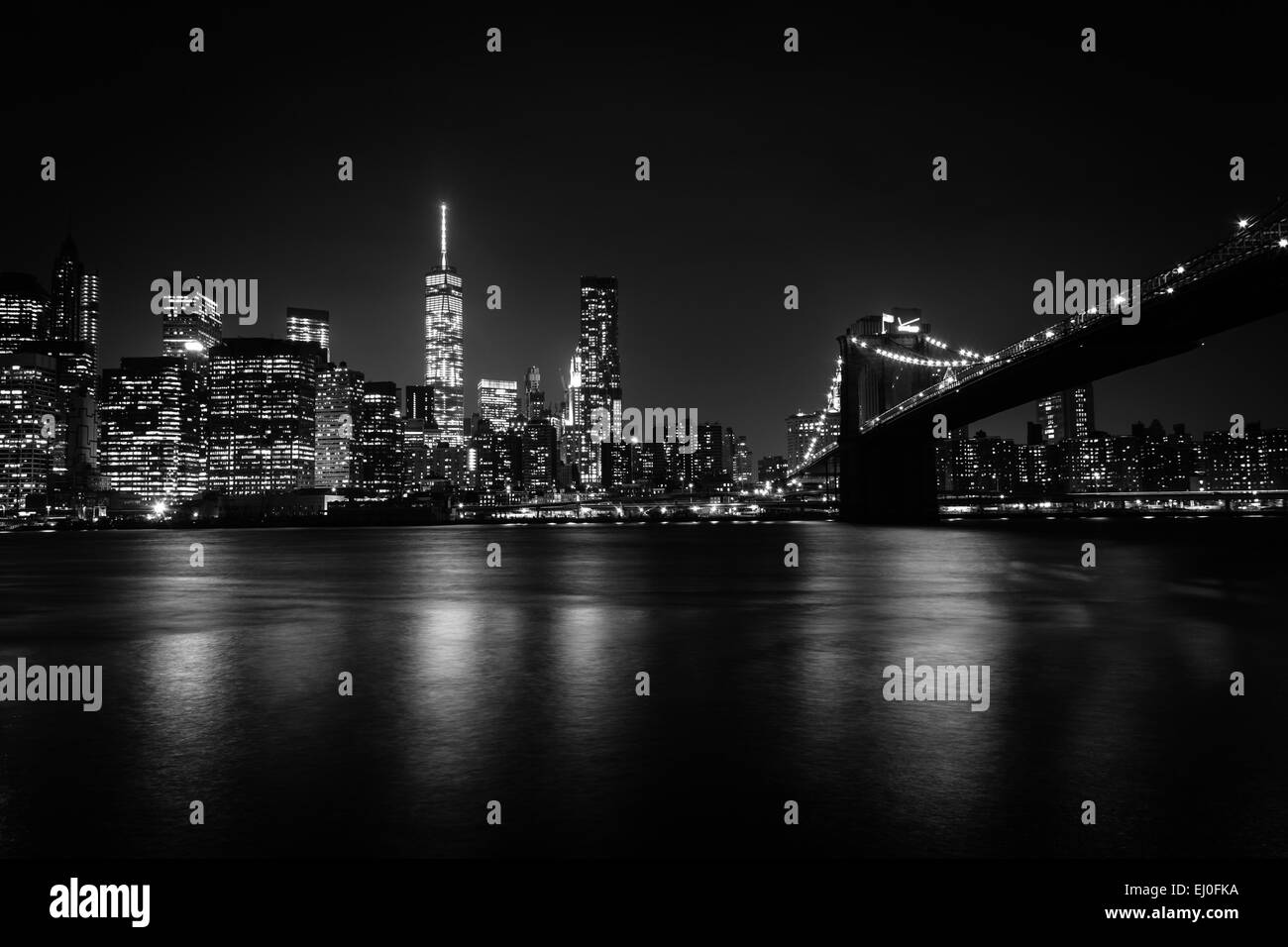 Die Skyline von Manhattan und die Brooklyn Bridge bei Nacht gesehen aus Brooklyn Bridge Park in Brooklyn, New York. Stockfoto