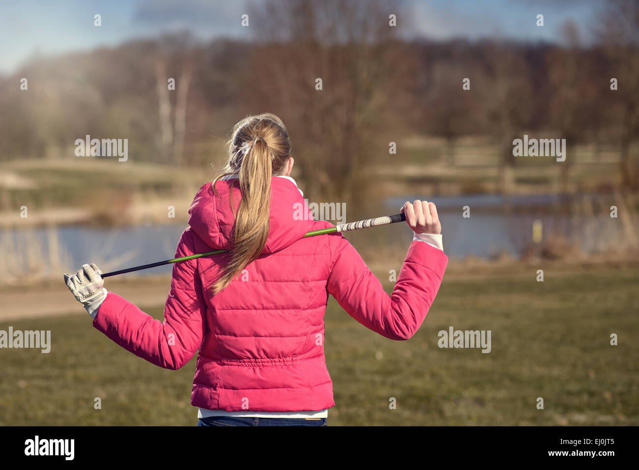 Junge Frau beim Golfen zu Fuß zurück zu ihrem Golf-Cart und Clubs quer über das Fairway, Ansicht von hinten Stockfoto