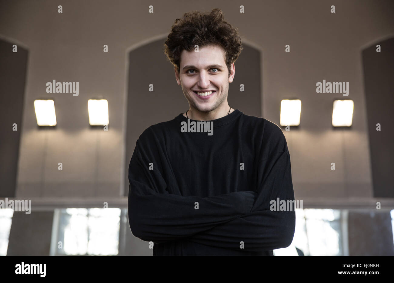 Porträt eines lächelnden jungen Mannes mit verschränkten Armen Stockfoto