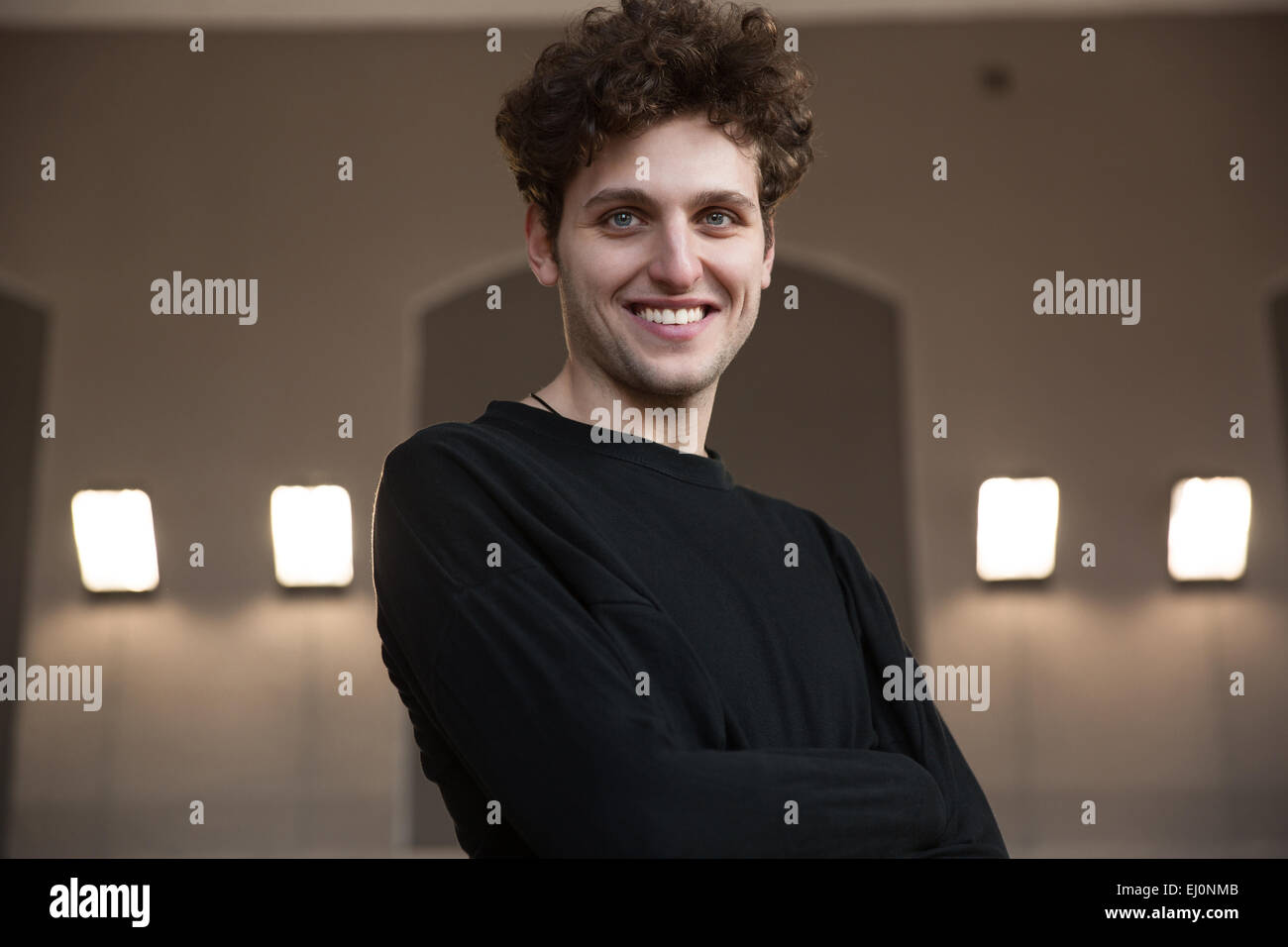 Glücklicher junger Mann mit verschränkten Armen Stockfoto