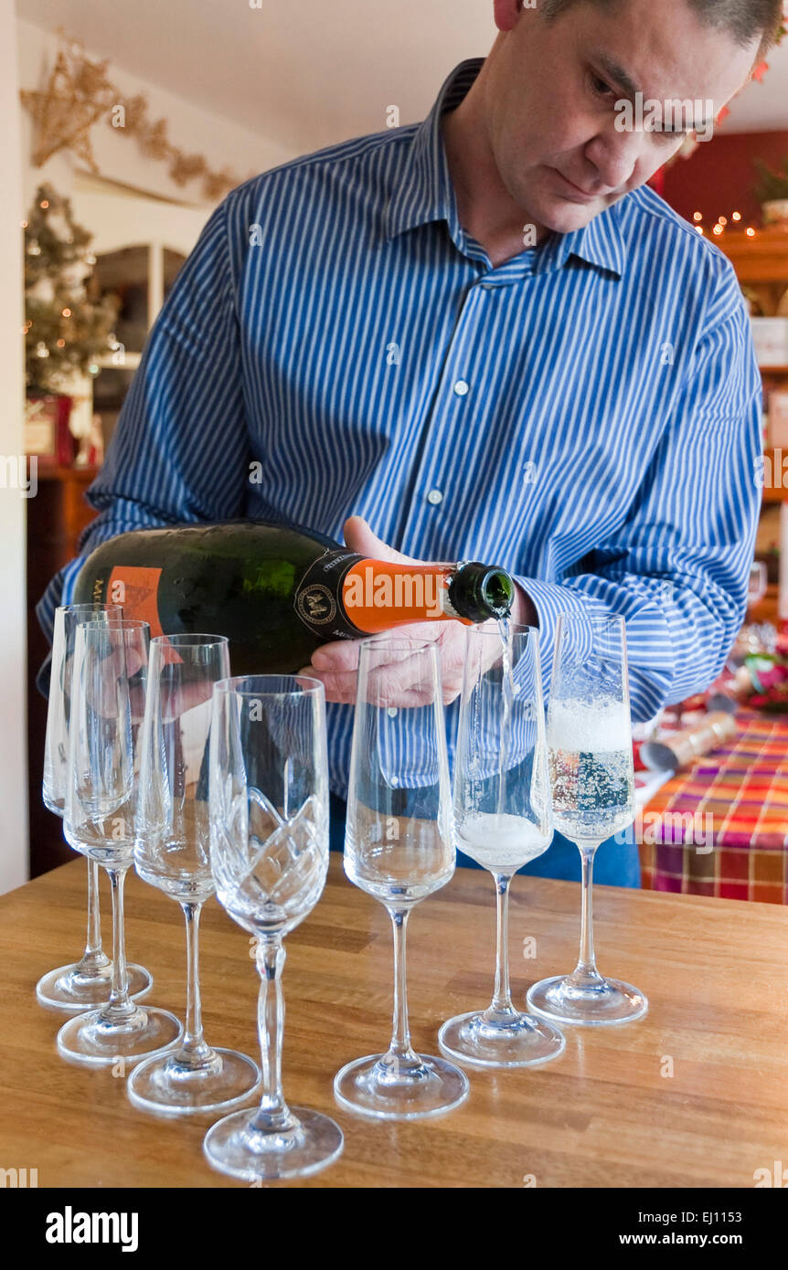 Vertikale Porträt eines Mannes gießt Champagner in Flöten zu Weihnachten. Stockfoto