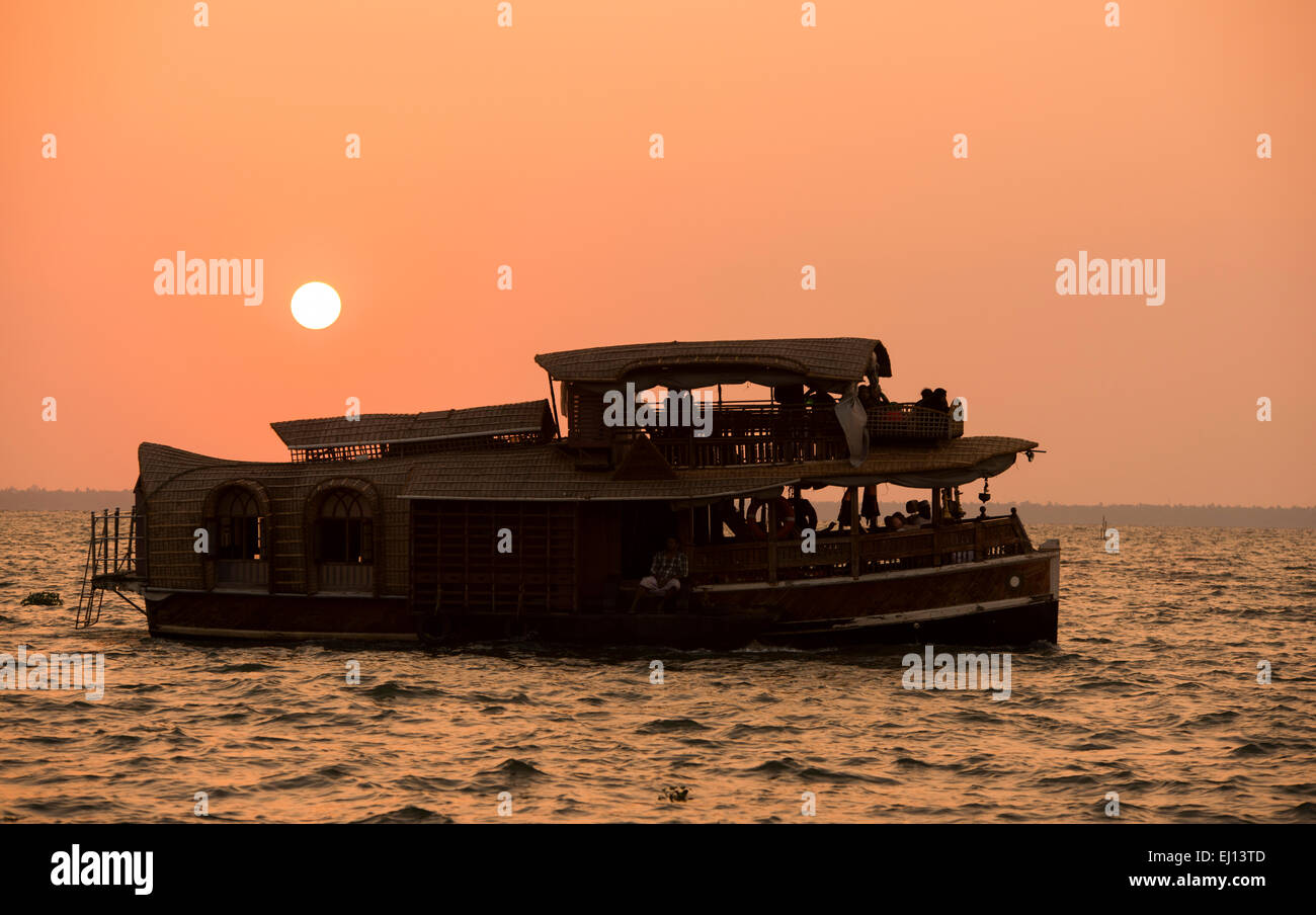 Ein Hausboot in der Silhouette bei Sonnenuntergang am Vembanad See in Kumarakom, Kerala Indien Stockfoto
