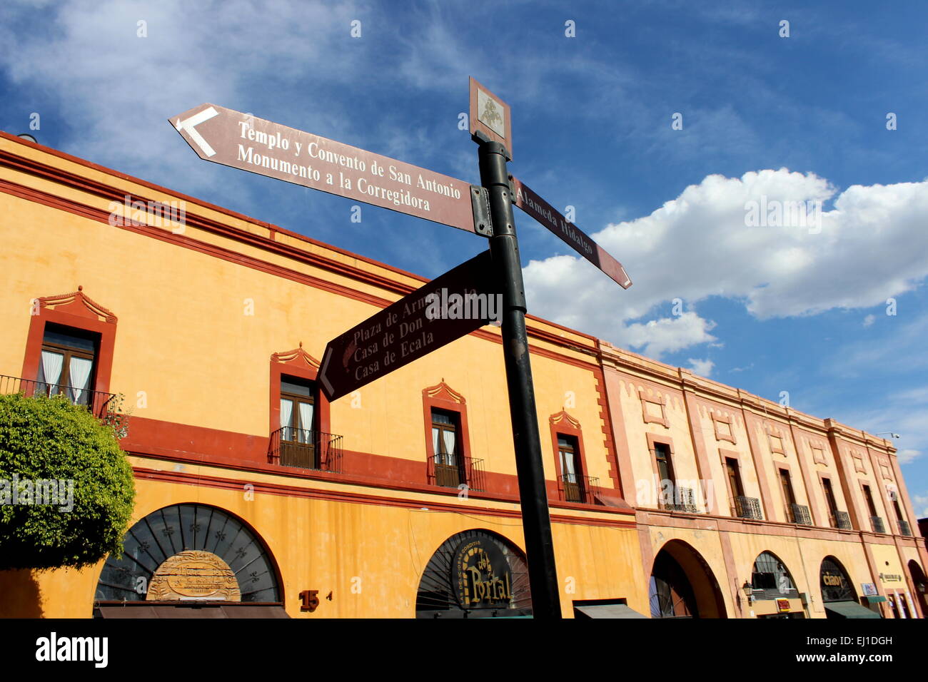 Gelbes Gebäude mit Wegweiser zu Websites und blauem Himmel und weißen Wolken in Queretaro, Bundesstaat Querétaro, Mexiko Stockfoto