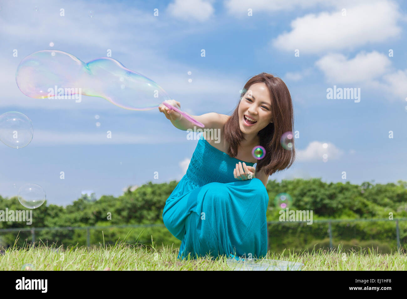 Junge Frau spielen Bubbles auf dem Rasen und glücklich lächelnd, Stockfoto