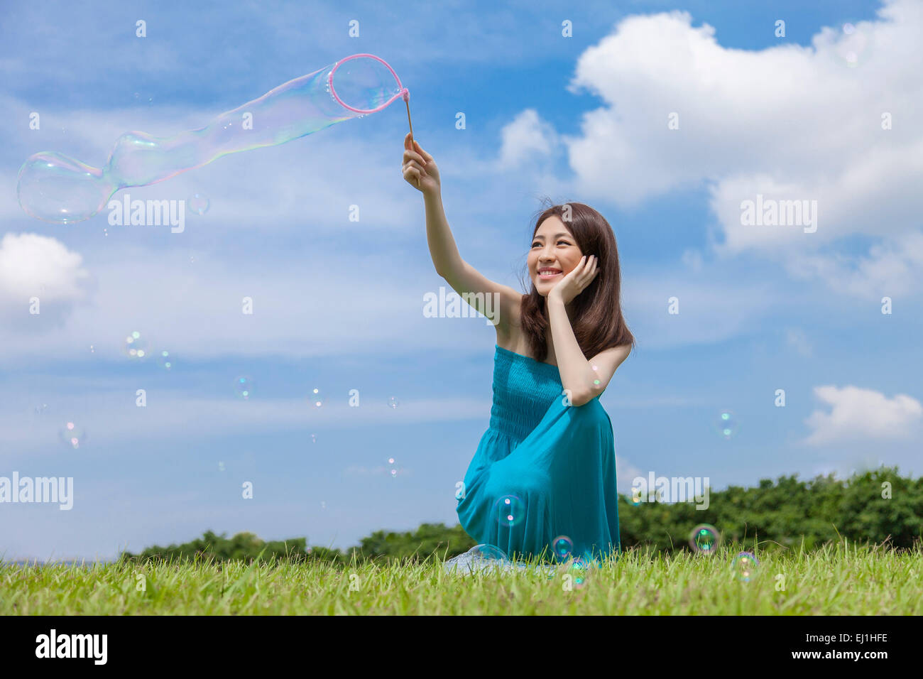 Junge Frau spielen Bubbles auf dem Rasen und glücklich lächelnd, Stockfoto