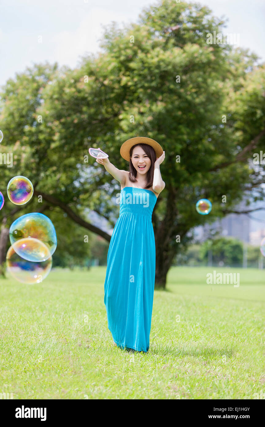 Junge Frau auf dem Rasen stehen und spielen Bubbles mit Lächeln, Stockfoto