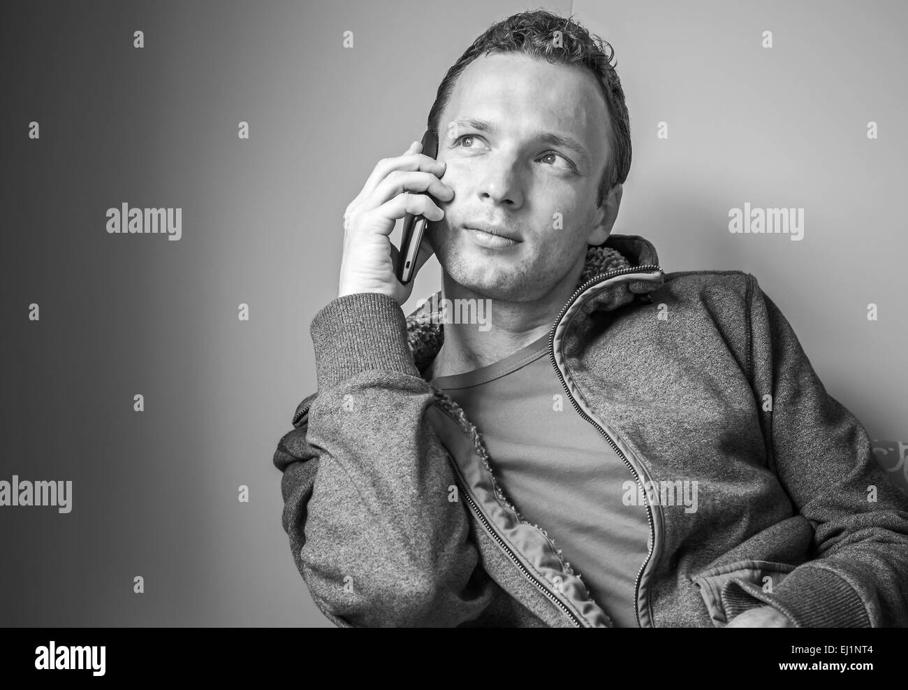 Monochrome Portrait sitzen junge Erwachsene kaukasischen Mann telefonieren mit Handy Stockfoto