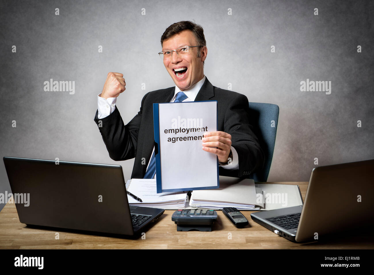 Geschäftsmann am Schreibtisch hält einen Arbeitsvertrag Stockfoto