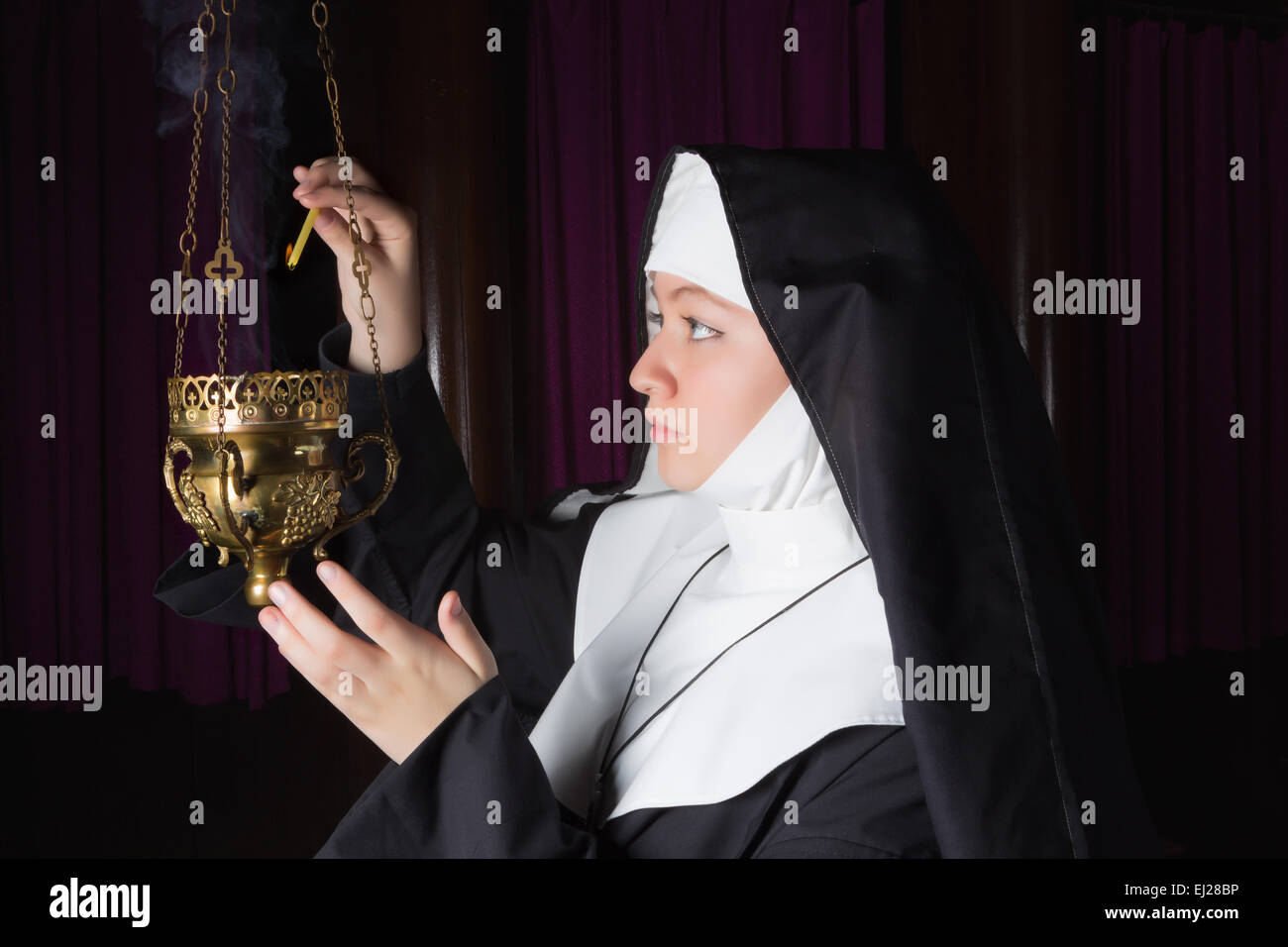 Nonne in Gewohnheit Beleuchtung Kupfer Räuchergefäß in Kirche Stockfoto