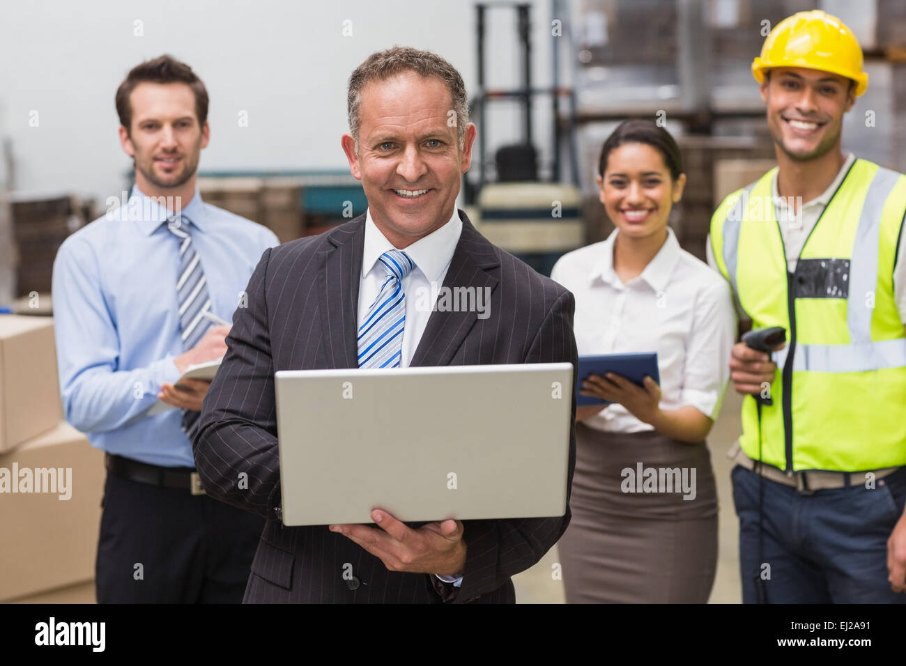 Lächelnd Chef mit Laptop vor seinen Mitarbeitern Stockfoto