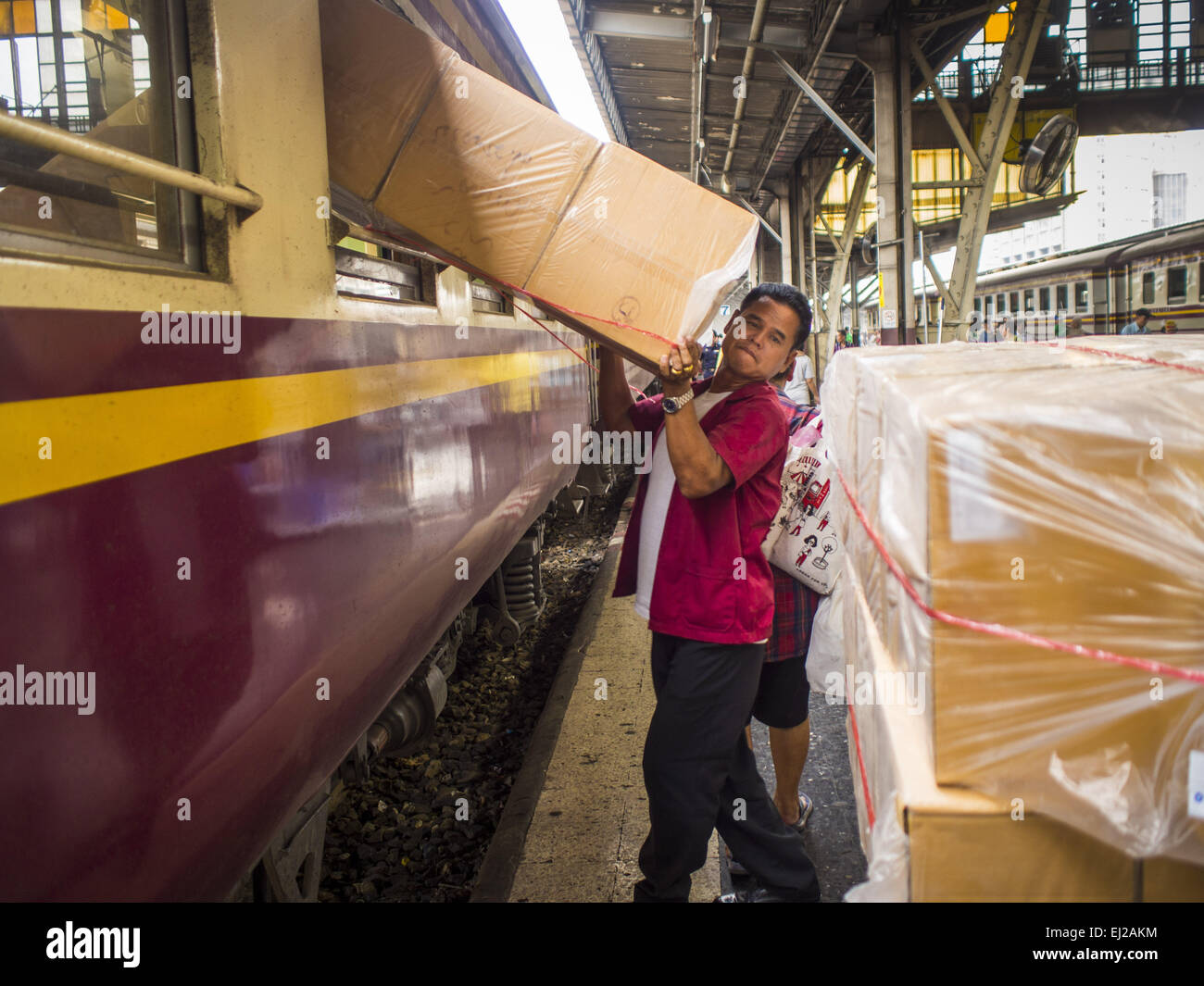 Bangkok, Bangkok, Thailand. 19. März 2015. Ein Mann wird Boxen durch das Fenster eines Zuges der dritten Klasse von Ayutthaya, nachdem der Zug am Bahnhof Hua Lamphong in Bangkok angekommen. Die staatliche Eisenbahn von Thailand (SRT), gegründet 1890, betreibt 4.043 Kilometer Meter Messgerät, das meisten Teilen von Thailand erreicht. Viel von der Strecke und viele der Züge sind in schlechtem Zustand und Züge fahren häufig spät. Unfälle und Pannen sind ebenfalls üblich. Aufeinanderfolgende Regierungen, einschließlich der aktuellen militärischen Regierung haben versprochen, Bahnverkehr zu aktualisieren. Die Militärregierung hat Stockfoto