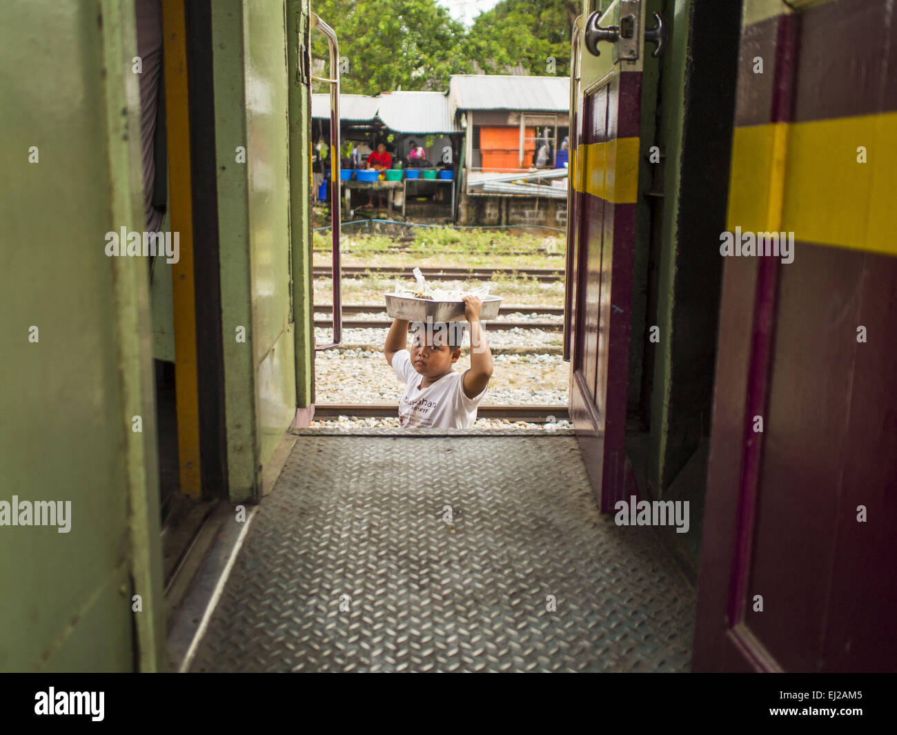 Prachinburi, Prachinburi, Thailand. 20. März 2015. Ein Kind arbeitet als Verkäufer geht zwischen den Autos in der Nähe des Bahnhofs Prachinburi. Er verkaufte Snacks für Passagiere Reiten eines 3. Klasse-Zuges nach Kabin Buri. Die staatliche Eisenbahn von Thailand (SRT), gegründet 1890, betreibt 4.043 Kilometer Meter Messgerät, das meisten Teilen von Thailand erreicht. Viel von der Strecke und viele der Züge sind in schlechtem Zustand und Züge fahren häufig spät. Unfälle und Pannen sind ebenfalls üblich. Aufeinanderfolgende Regierungen, einschließlich der aktuellen militärischen Regierung haben versprochen, Bahnverkehr zu aktualisieren. Stockfoto