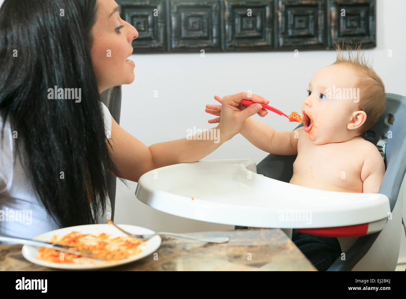 Mutter, die hungrigen sechs Monate altes Baby feste Nahrung Stockfoto