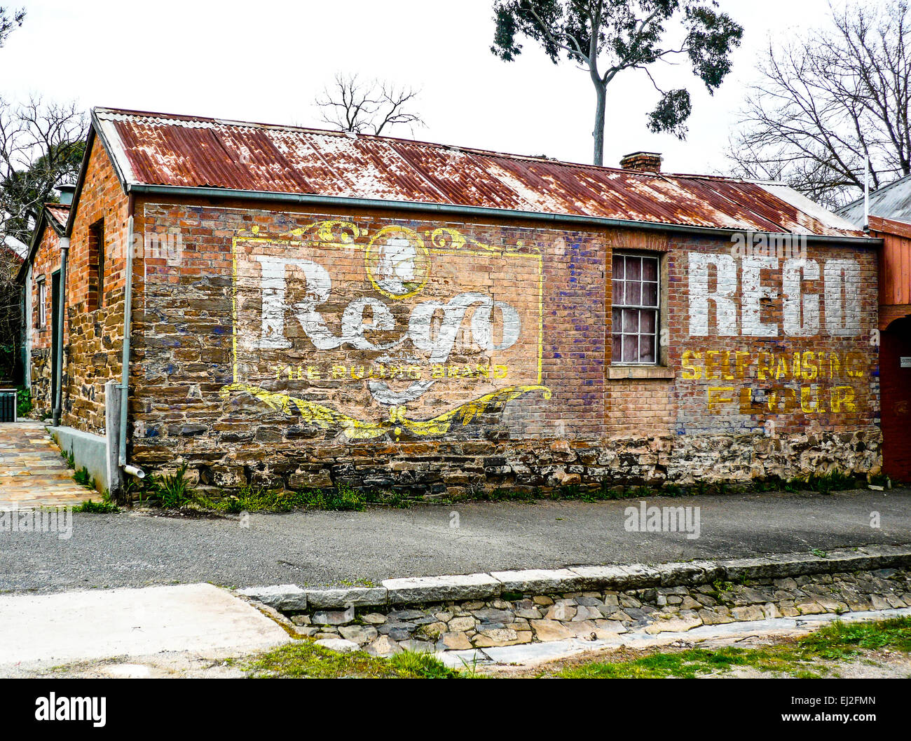 Reste der gemalten Werbung bleiben als gespenstische Bild auf roten Ziegel der alten Gebäude in Maldon, zentrale Victoria, Australien. Stockfoto