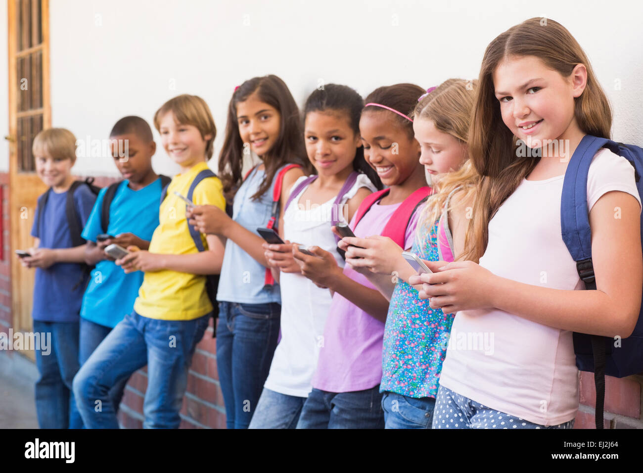 Niedlichen Schülerinnen und Schüler mit Handy Stockfoto