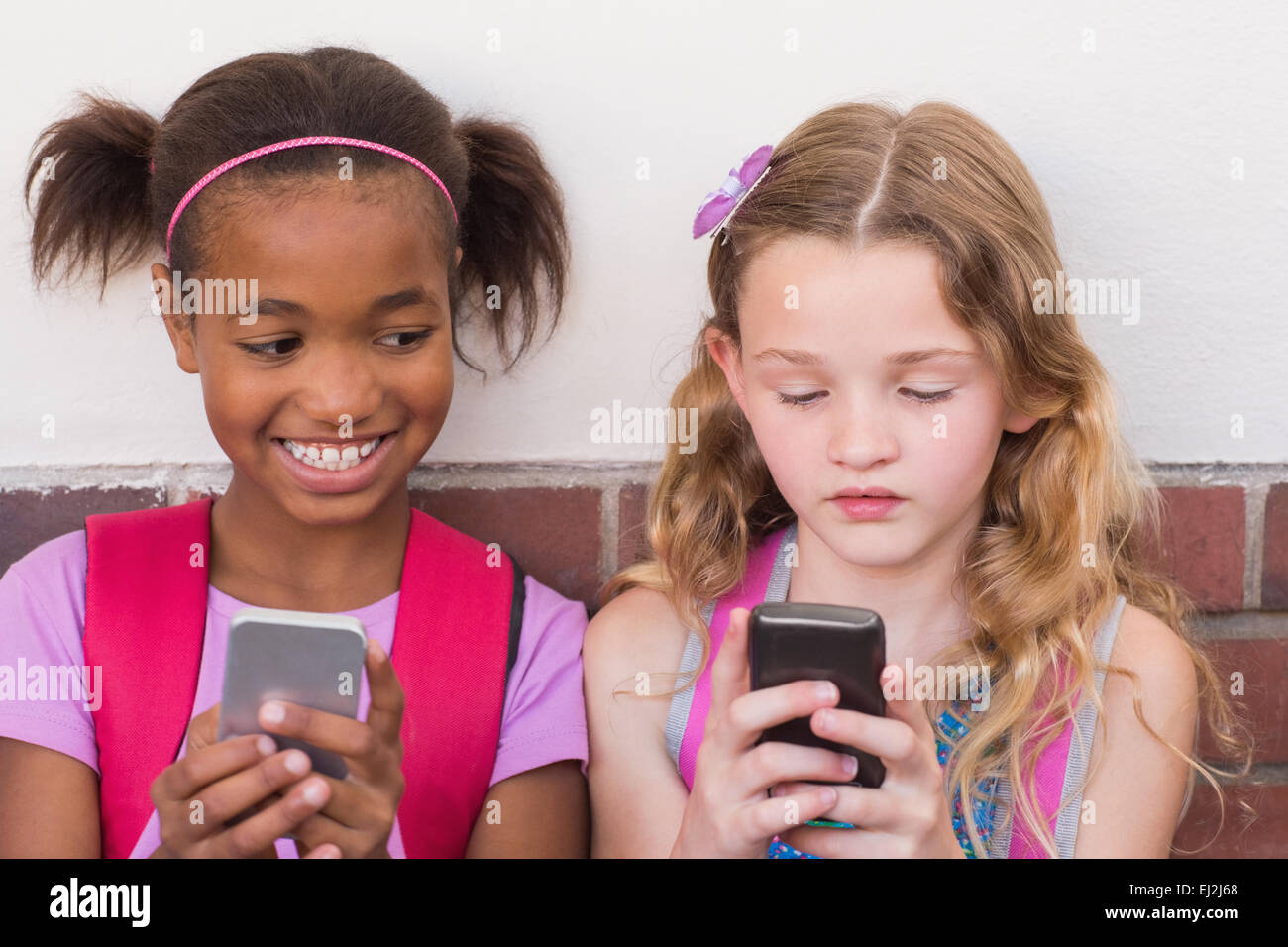 Niedlichen Schülerinnen und Schüler mit Handy Stockfoto