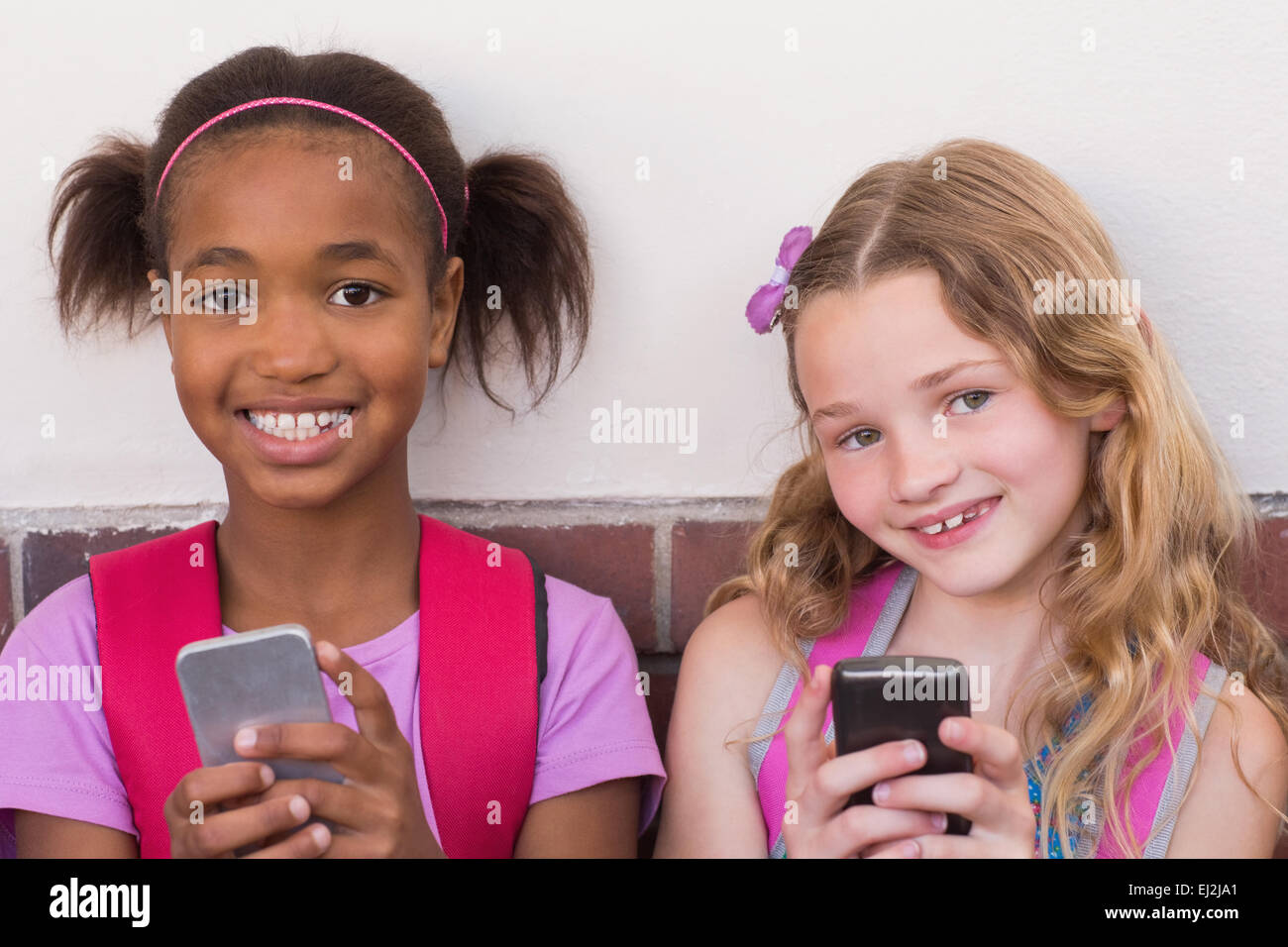 Niedlichen Schülerinnen und Schüler mit Handy Stockfoto