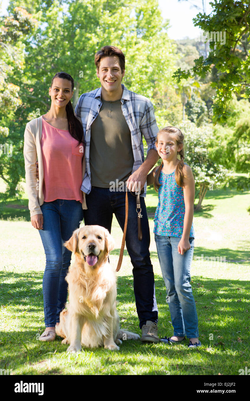 Glückliche Familie, die ihren Hund im Park spazieren gehen Stockfoto