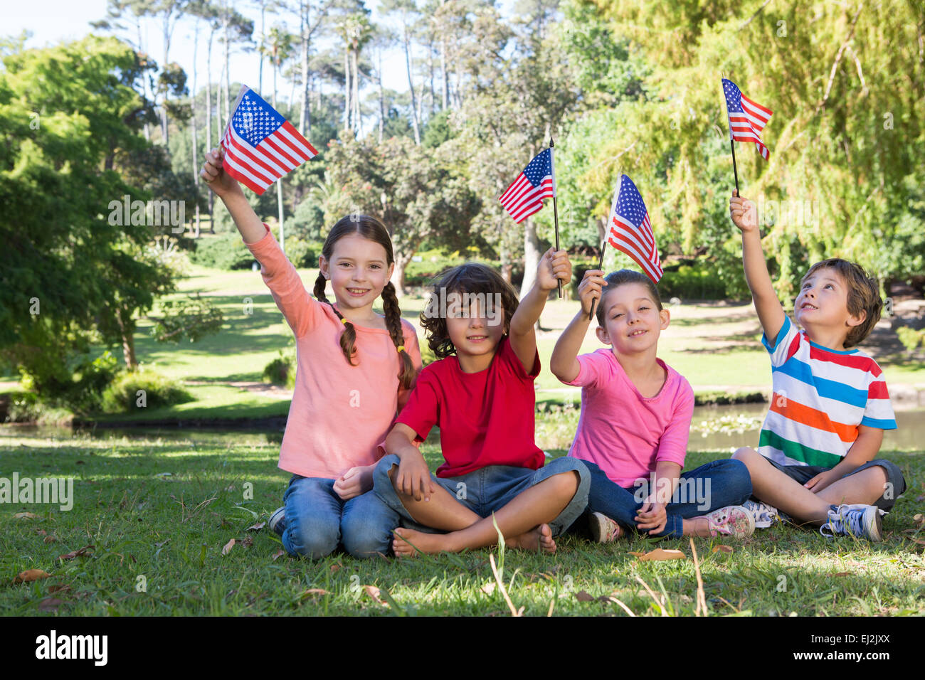 Glückliche kleine Freunde, die amerikanische Flagge winken Stockfoto