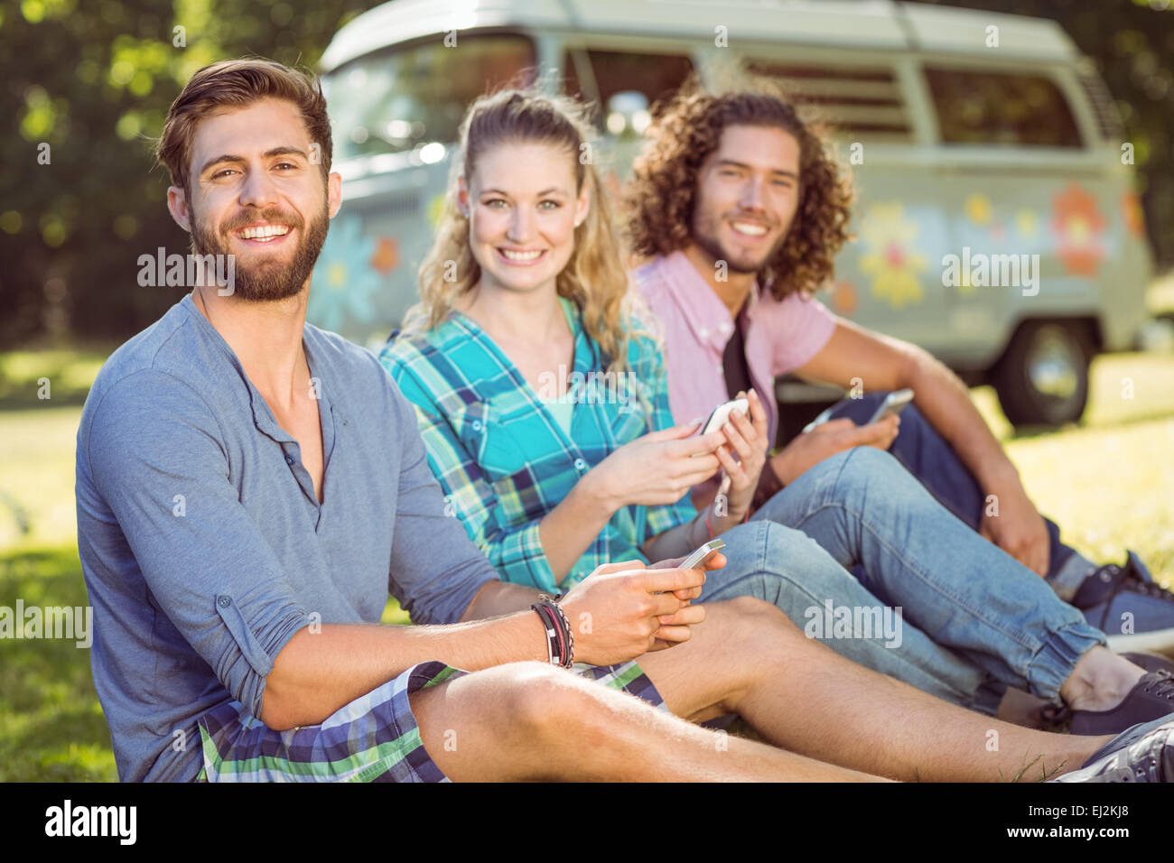 Hipster, die sitzen auf dem Rasen-SMS Stockfoto
