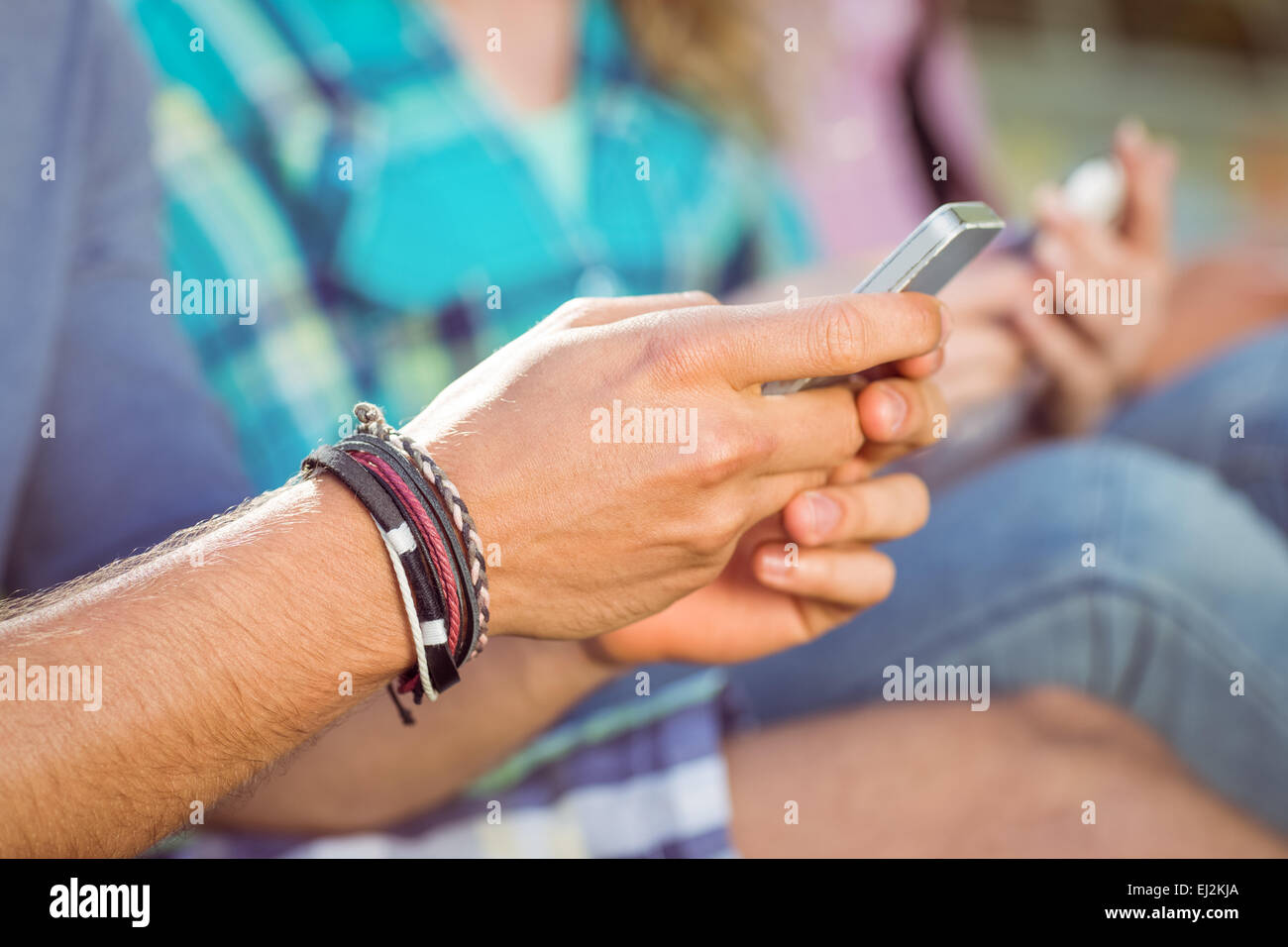 Hipster, die sitzen auf dem Rasen-SMS Stockfoto