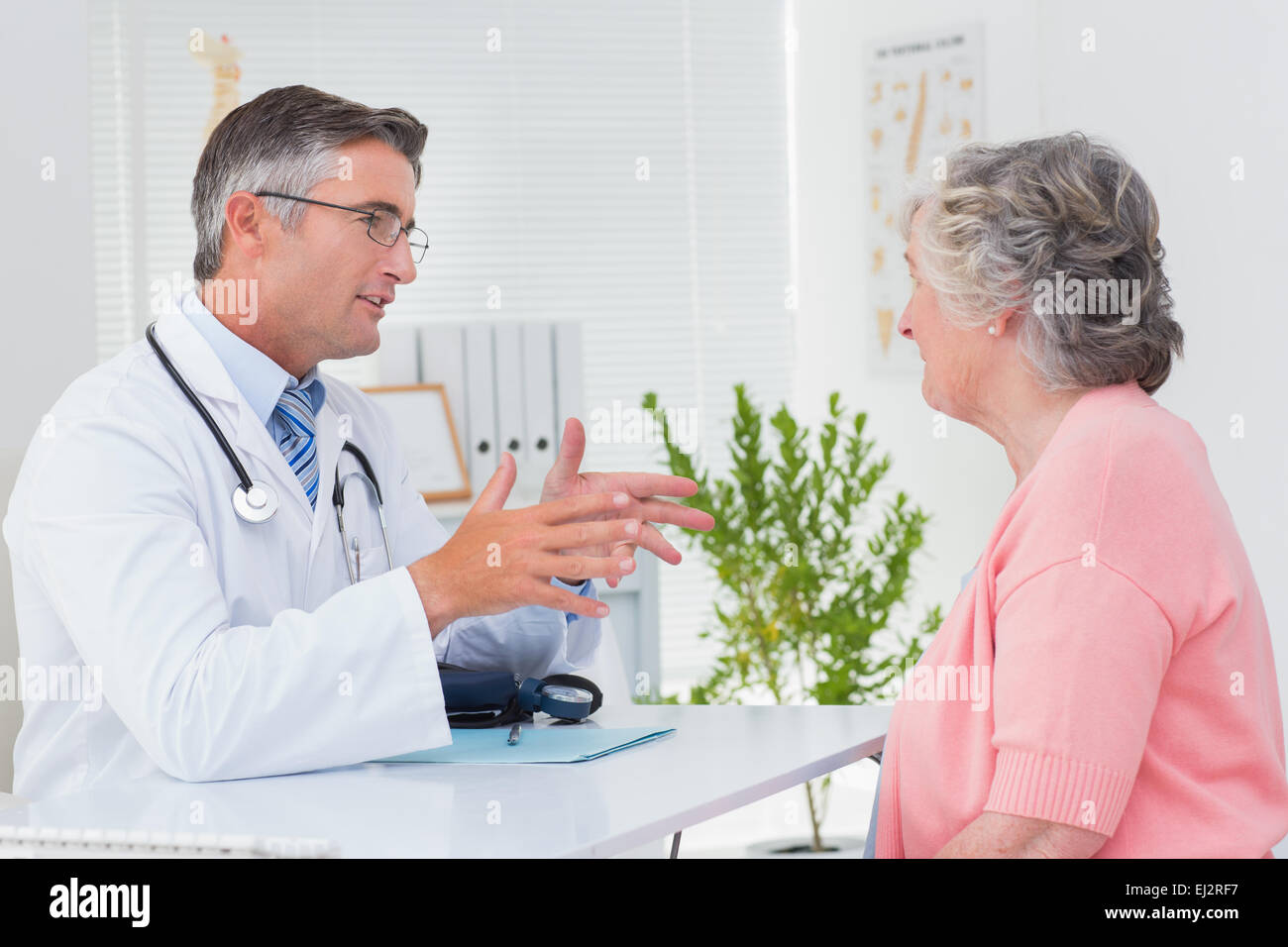 Männlichen Arzt im Gespräch mit der Patientin am Tisch Stockfoto